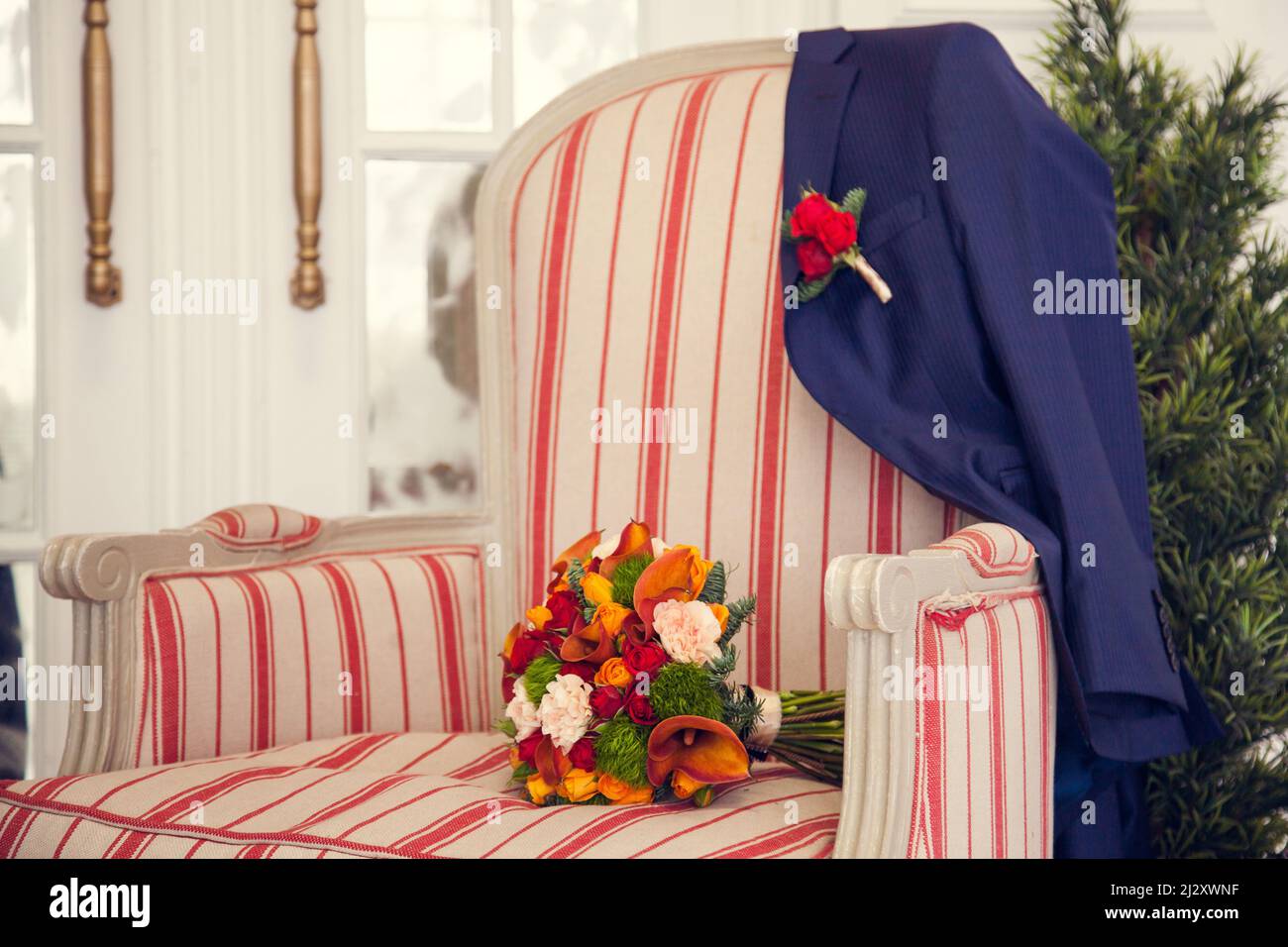 Le bouquet de la mariée et la veste du marié avec une boutonnière sur un ancien fauteuil rembourré dans la chambre à coucher pendant Noël. Hiver et Noël Banque D'Images