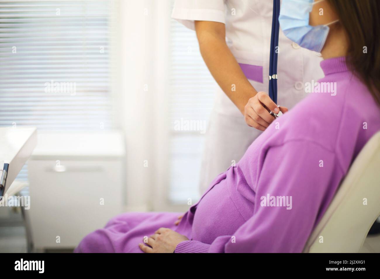 Médecin écoutant le rythme cardiaque de la femme enceinte avec stéthoscope lors d'un rendez-vous de soins prénatals à l'hôpital, dose de culture.Maladie cardiaque pendant la grossesse Banque D'Images