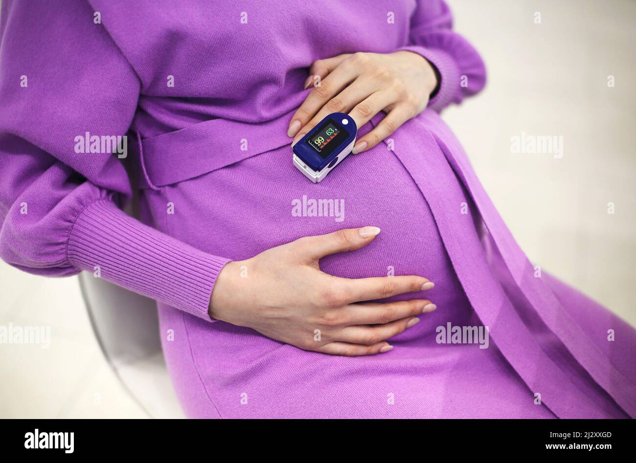 Femme enceinte avec oxymètre de pouls sur le doigt.Médecin mesurant le niveau de saturation en oxygène lors de la visite d'une mère enceinte atteinte de coronavirus au hom Banque D'Images