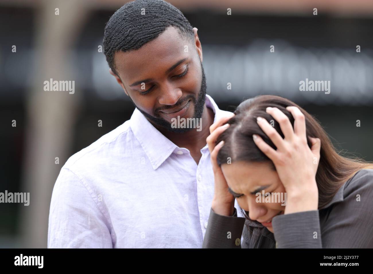 Un ami hypocrite réconfortant une femme triste dans la rue Banque D'Images