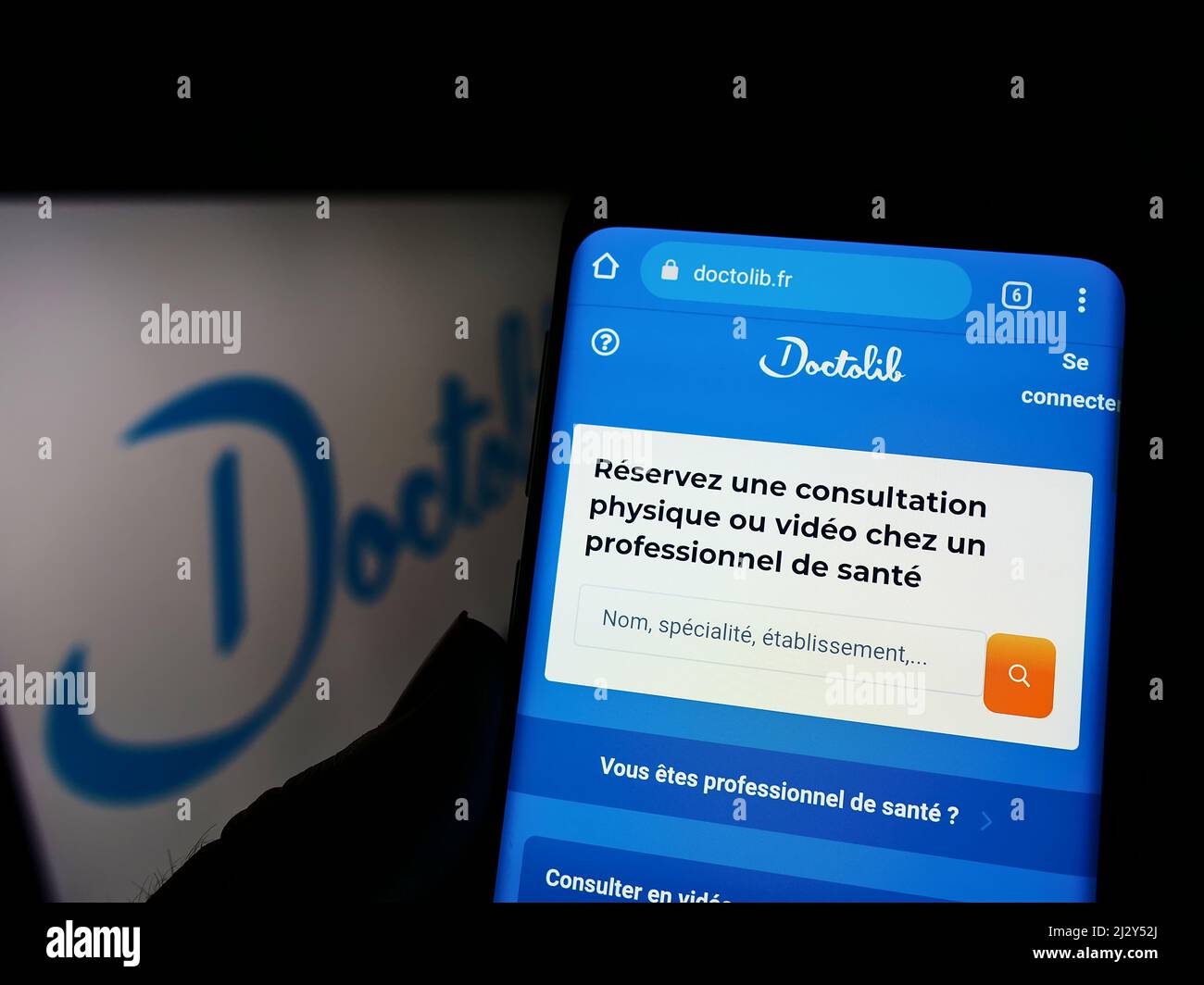 Personne tenant un téléphone portable avec le site Internet de la société française de soins de santé Doctolib SAS à l'écran devant le logo. Concentrez-vous sur le centre de l'écran du téléphone. Banque D'Images