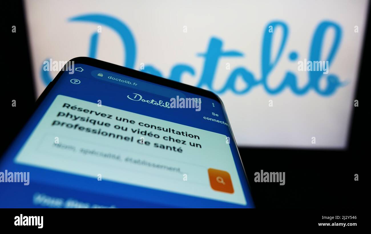 Smartphone avec page web de la société française de santé Doctolib SAS à l'écran devant le logo de l'entreprise. Faites la mise au point dans le coin supérieur gauche de l'écran du téléphone. Banque D'Images