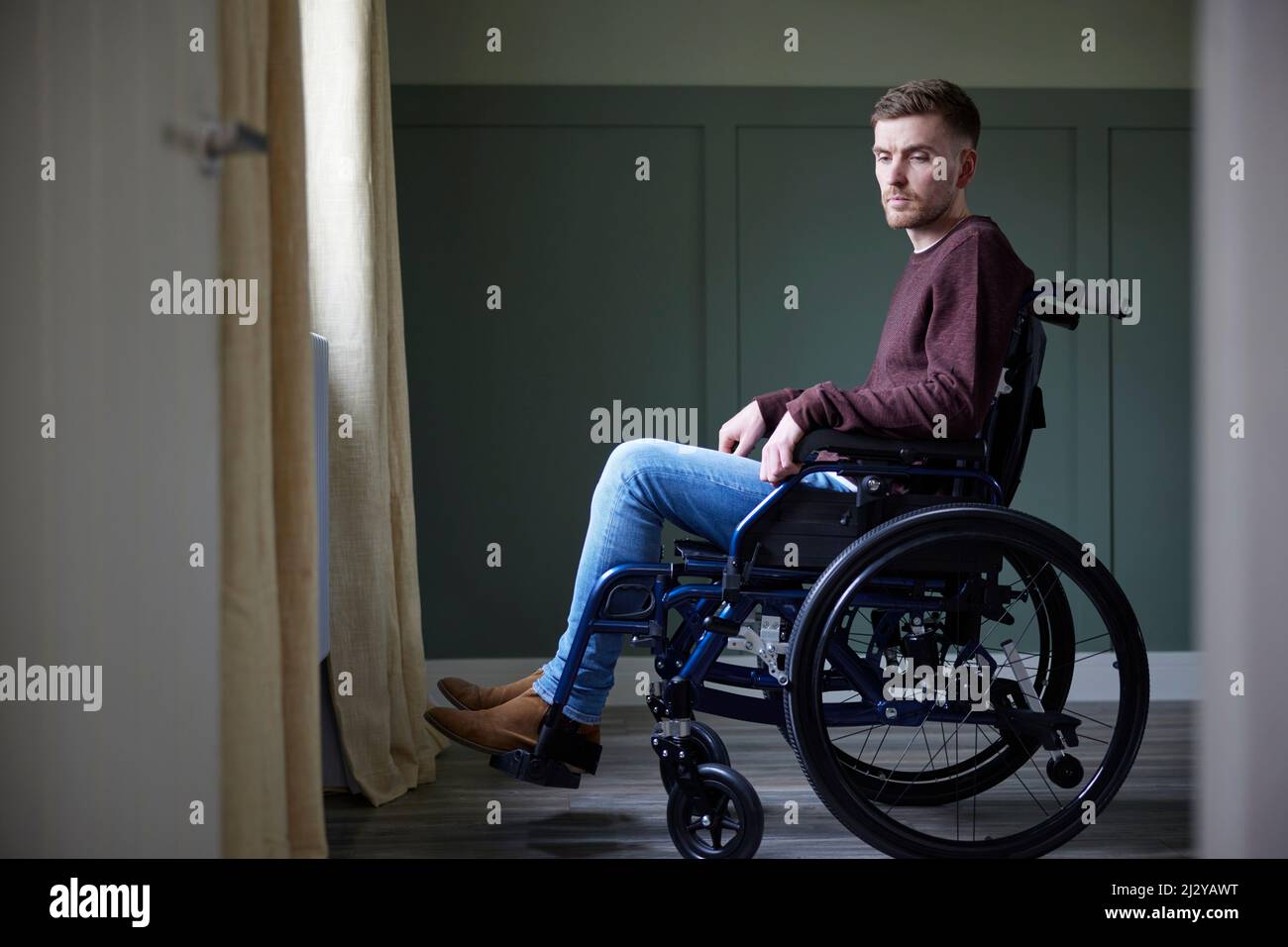 Dépression jeune homme avec mauvaise santé mentale en fauteuil roulant par fenêtre à la maison Banque D'Images
