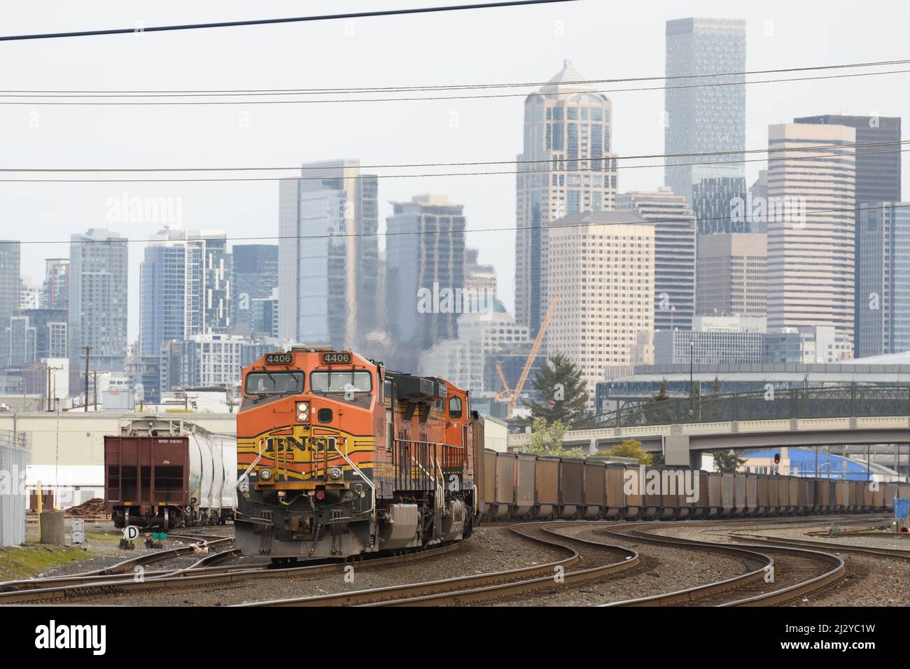 Seattle - le 03 avril 2022; le train à charbon chargé de BNSF traverse le centre-ville de Seatte avec la ligne d'horizon en arrière-plan Banque D'Images