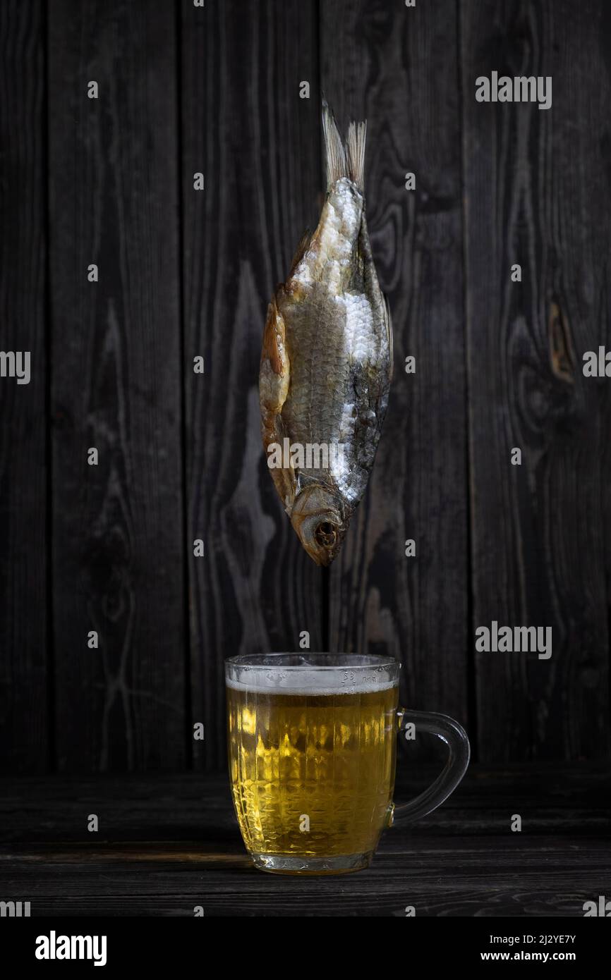 poisson vobla salé et séché avec bière ambrée sur fond de bois sombre dans un style minimaliste Banque D'Images