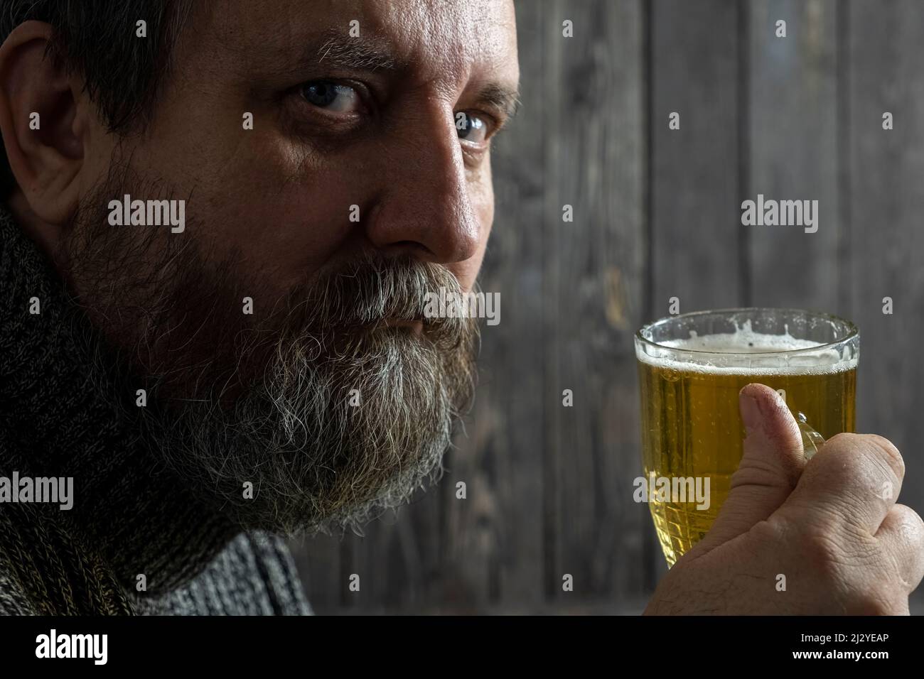 barbu un homme brutal adulte qui boit de la bière légère dans une tasse Banque D'Images