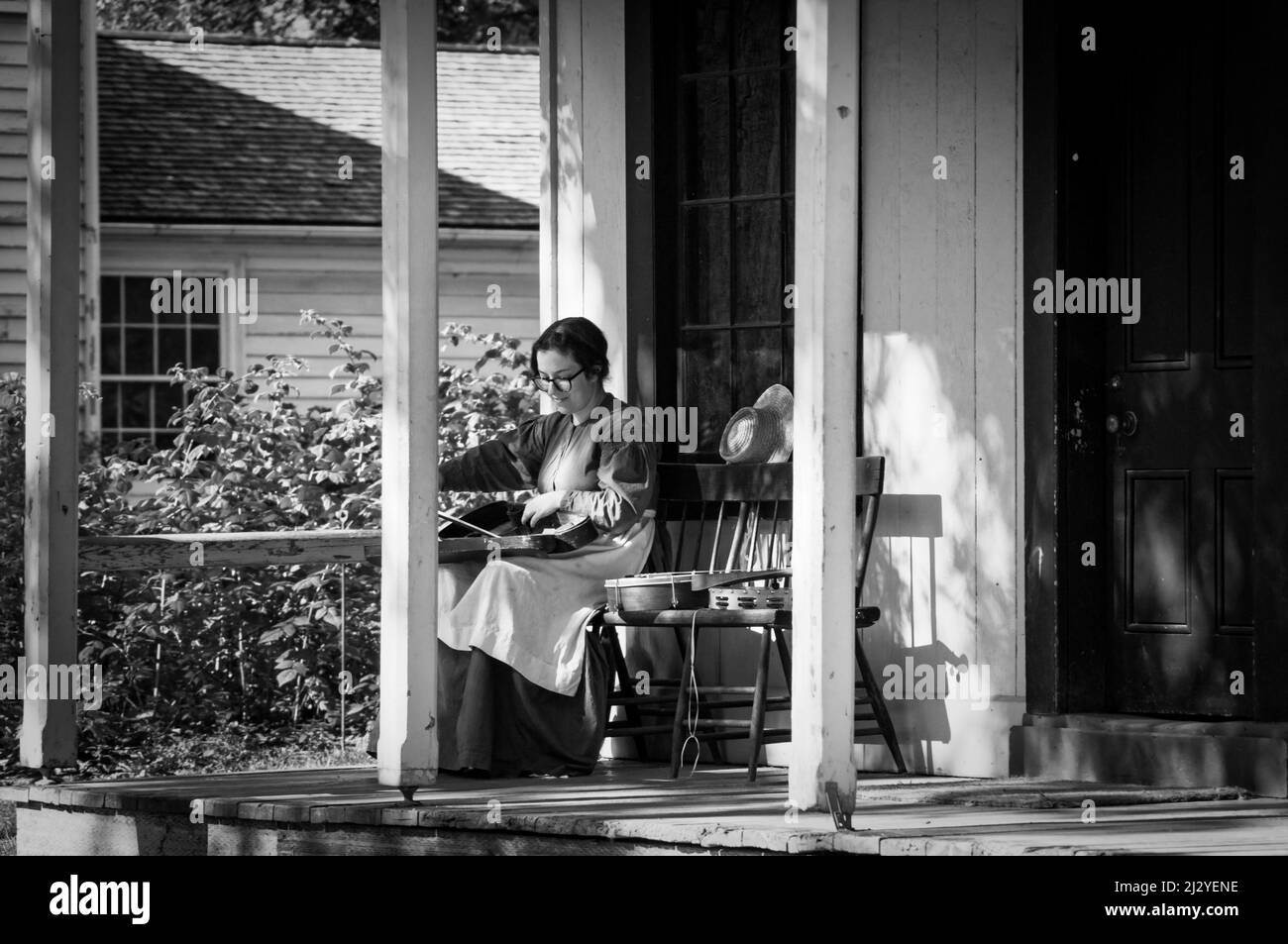 Toronto, Canada - 2019 08 24: Une femme portant un costume de style 19th siècle emboîte son violon dans l'étui sur le porche de l'ancienne maison en bois de l'op Banque D'Images