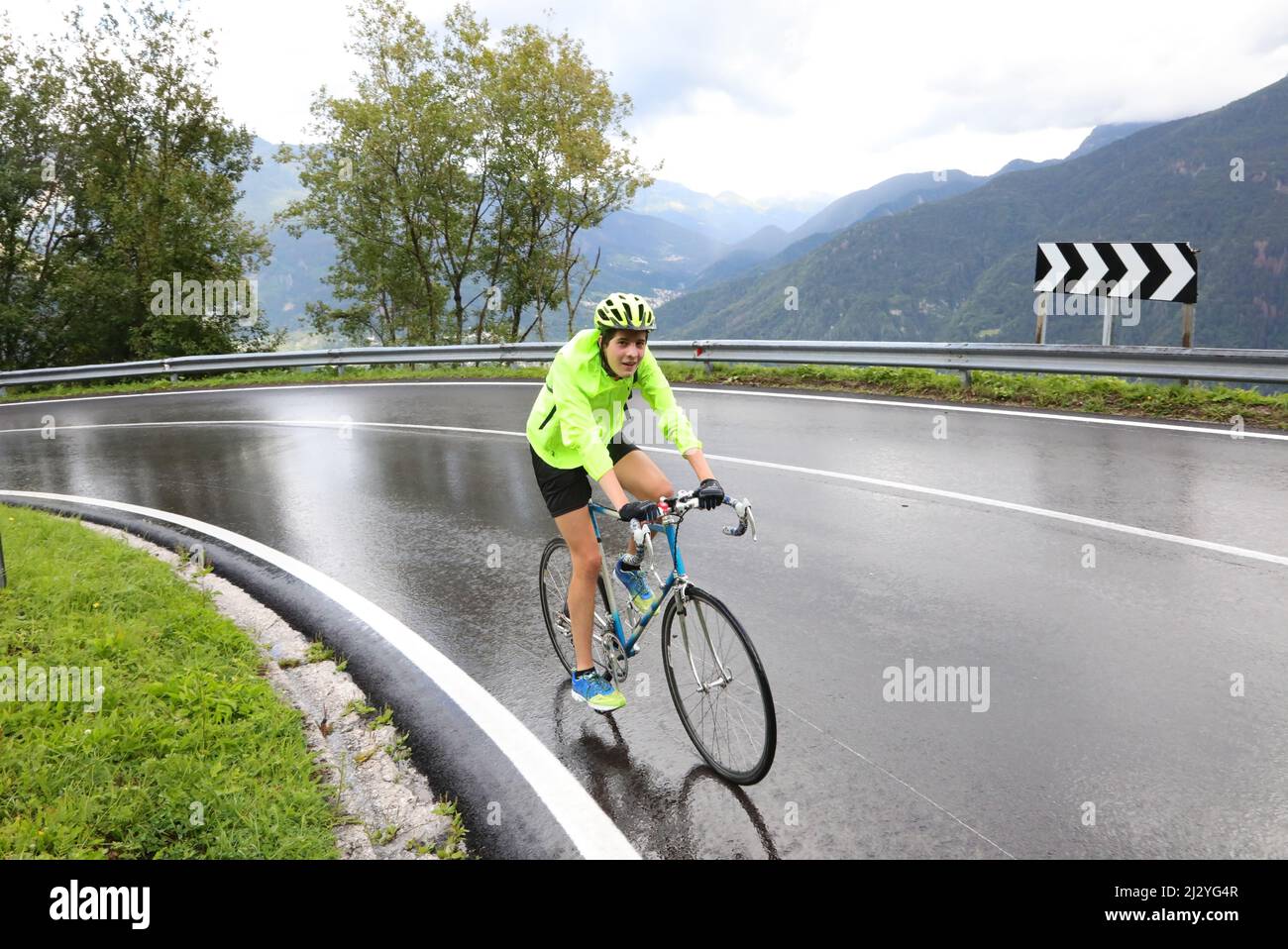 cycliste jeune garçon avec vélo de course tout en faisant une courbe sur route humide pendant l'entraînement sportif pendant la pluie Banque D'Images