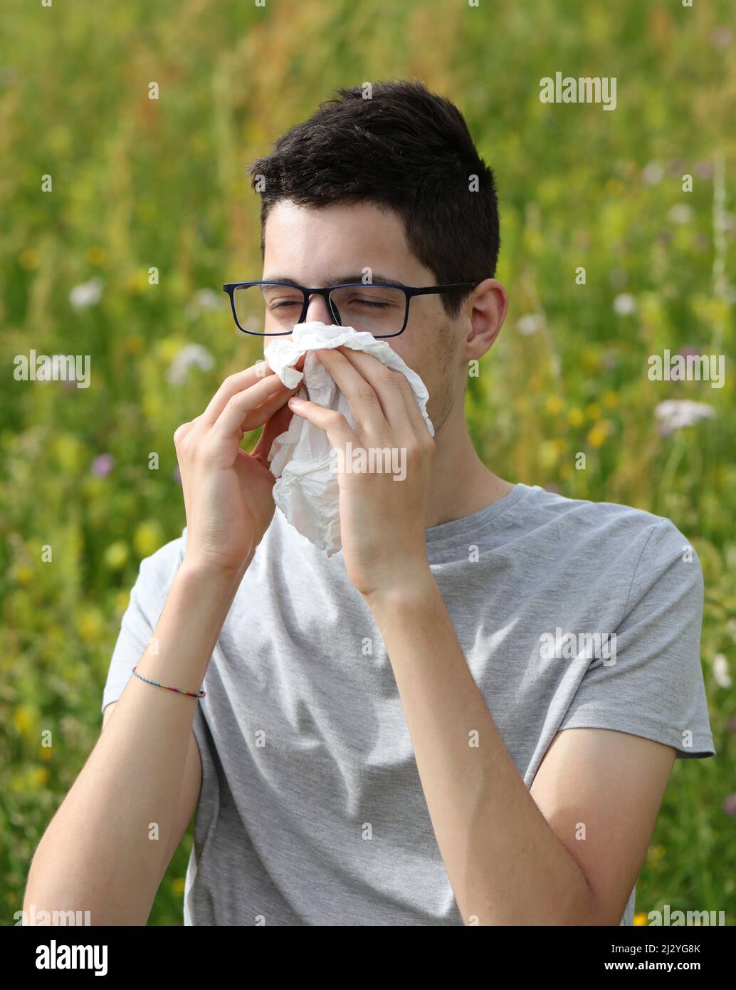 garçon allergique avec des lunettes éternuant sur un mouchoir blanc parce  qu'il a une allergie à l'herbe Photo Stock - Alamy