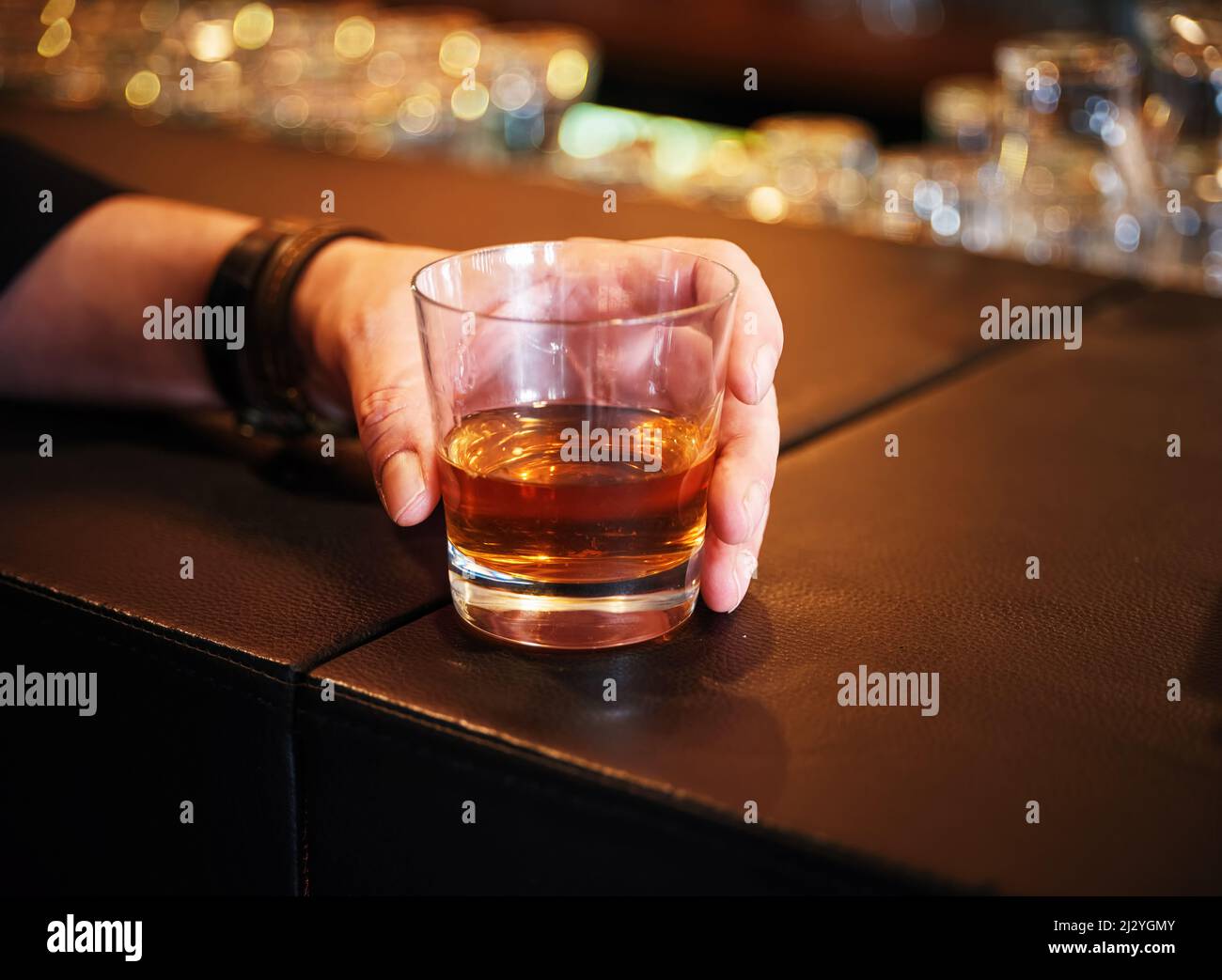 La main mâle tient un verre de whisky sur le comptoir. Banque D'Images