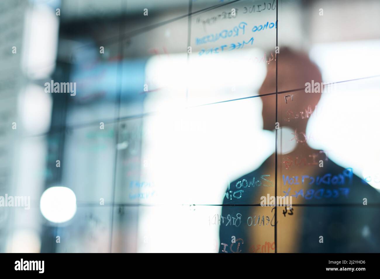 Travaillez à faire de vos grandes idées des choses. Photo d'un homme d'affaires brainstorming avec des notes sur un mur de verre dans un bureau. Banque D'Images