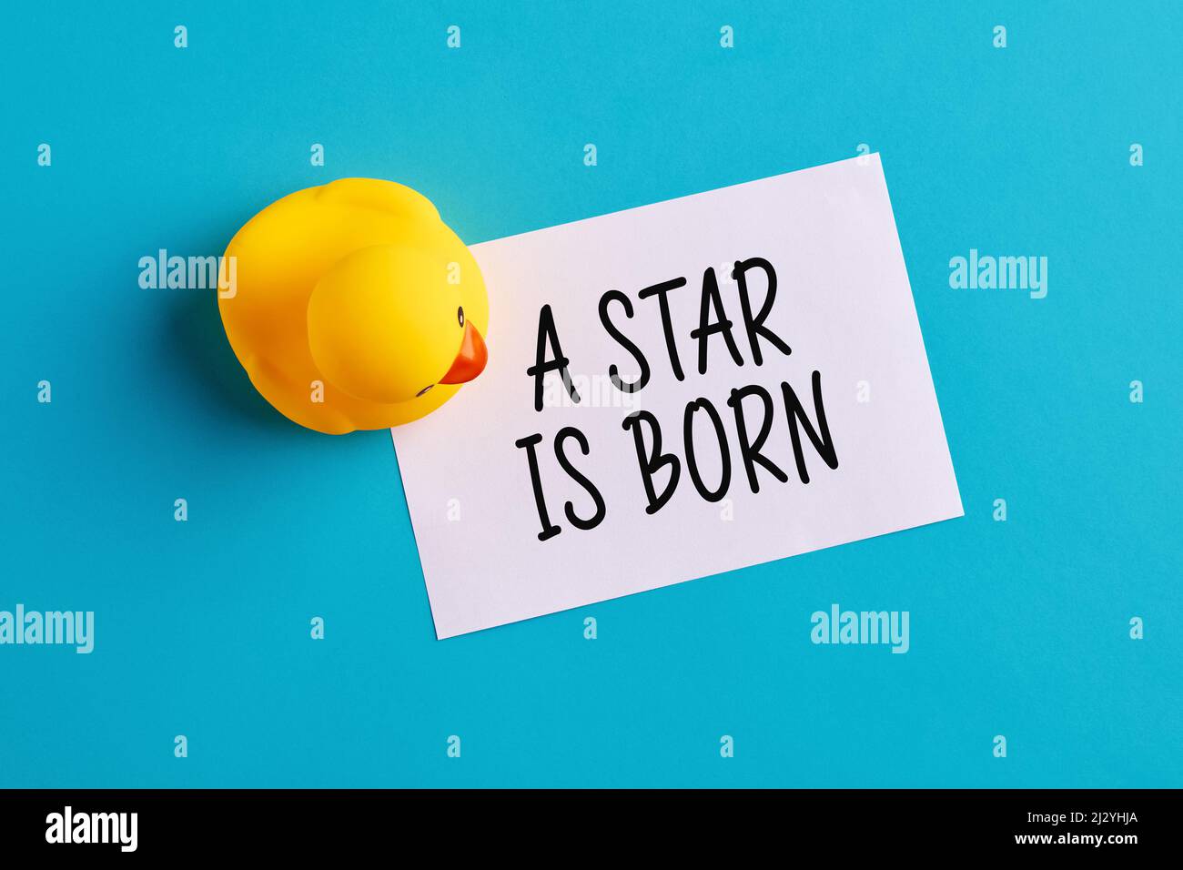 Une étoile est née écrite sur un papier à notes avec un jouet en caoutchouc duckling sur fond bleu. Message de célébration ou d'annonce de naissance du nouveau-né. Banque D'Images
