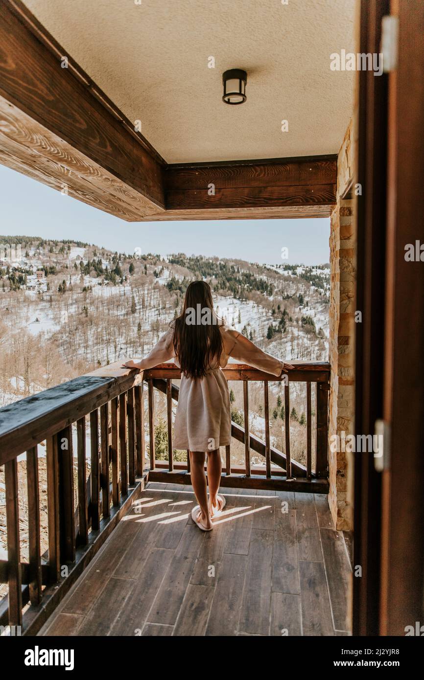 Vue arrière de la charmante jeune femme en peignoir profitant de la nature hivernale sur la grande terrasse Banque D'Images