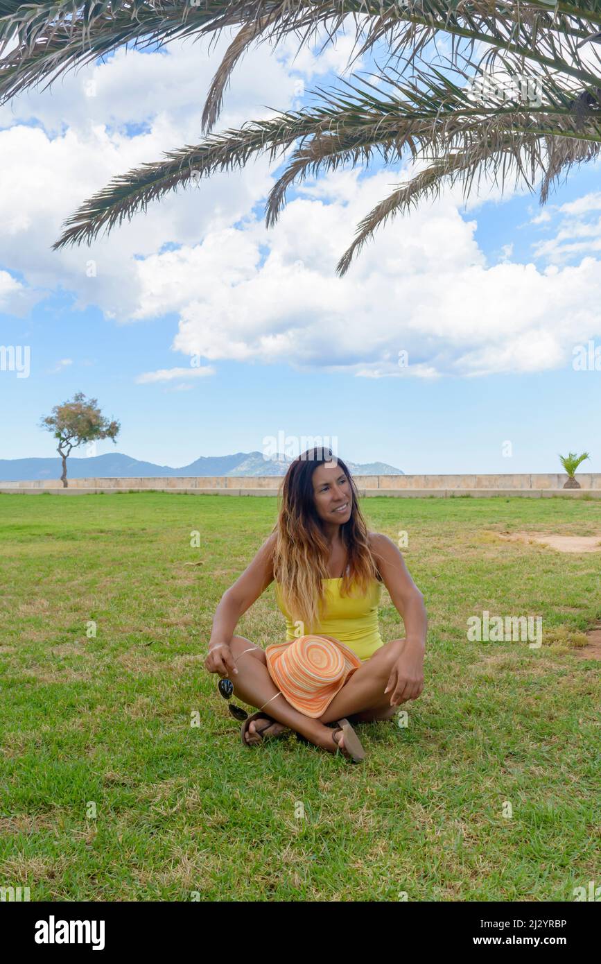 portrait d'une femme latine souriant, s'amusant, en vacances à majorque posant sur une chaude journée de printemps d'été, sous un palmier, concept de vacances Banque D'Images