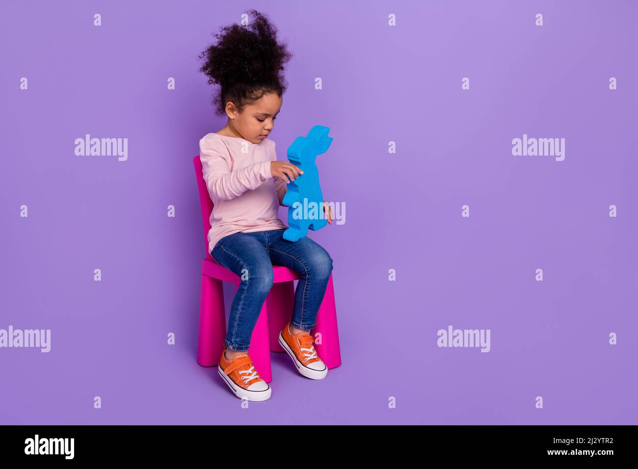 Vue sur toute la longueur du corps de la belle fille avant-adolescence tendance jouant festal jouet isolé sur fond violet vif de couleur violet Banque D'Images