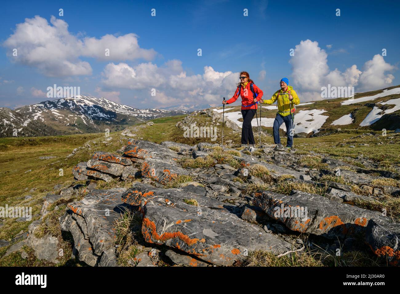 Homme et femme randonnée sur Königstuhl, rochers couverts de lichen en premier plan, Königstuhl, Nockberge, Nockberge-Trail, Parc de la biosphère de Nockberge, Alpes de Gurktal, Carinthie, Autriche Banque D'Images