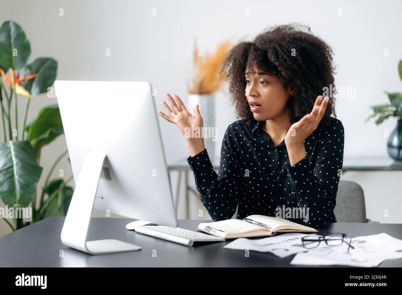 Surprise bouleversée jeune adulte mauriquement aux cheveux afro-américains femme d'affaires, gestionnaire ou courtier assis à une table, regarde l'ordinateur, choqué par les nouvelles ou les messages, a subi des pertes financières, perplexe Banque D'Images