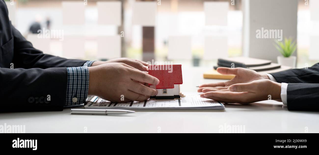 Les agents immobiliers acceptent d'acheter une maison et de donner un modèle de maison aux clients dans les bureaux de leur agence. Accord de concept Banque D'Images