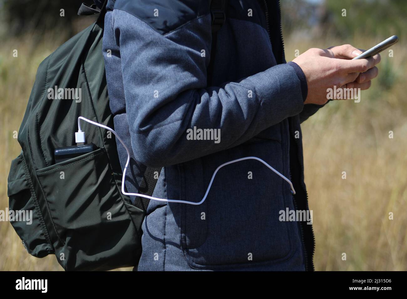 Homme marchant dans la nature et charge son smartphone avec la banque d'alimentation. Chargeur de voyage portable. Banque D'Images