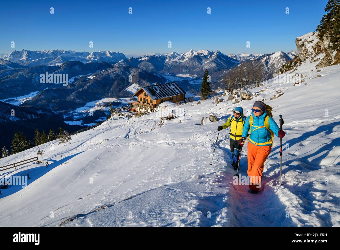 Homme et femme en randonnée sur les pistes de neige jusqu'à Hochgern, Hochgernhaus en arrière-plan, Hochgern, Alpes de Chiemgau, haute-Bavière, Bavière, Allemagne Banque D'Images