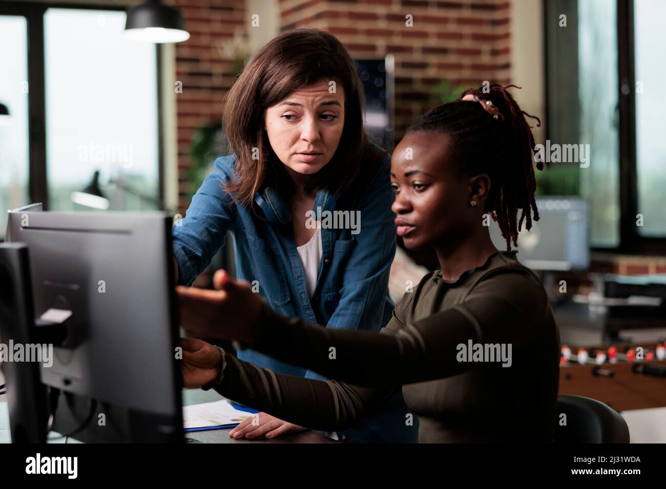 Artiste numérique afro-américain discutant avec le chef d'équipe de logiciels de conception. Des employés multiraciaux qui ont parlé du développement de logiciels et de la façon de l'améliorer. Banque D'Images