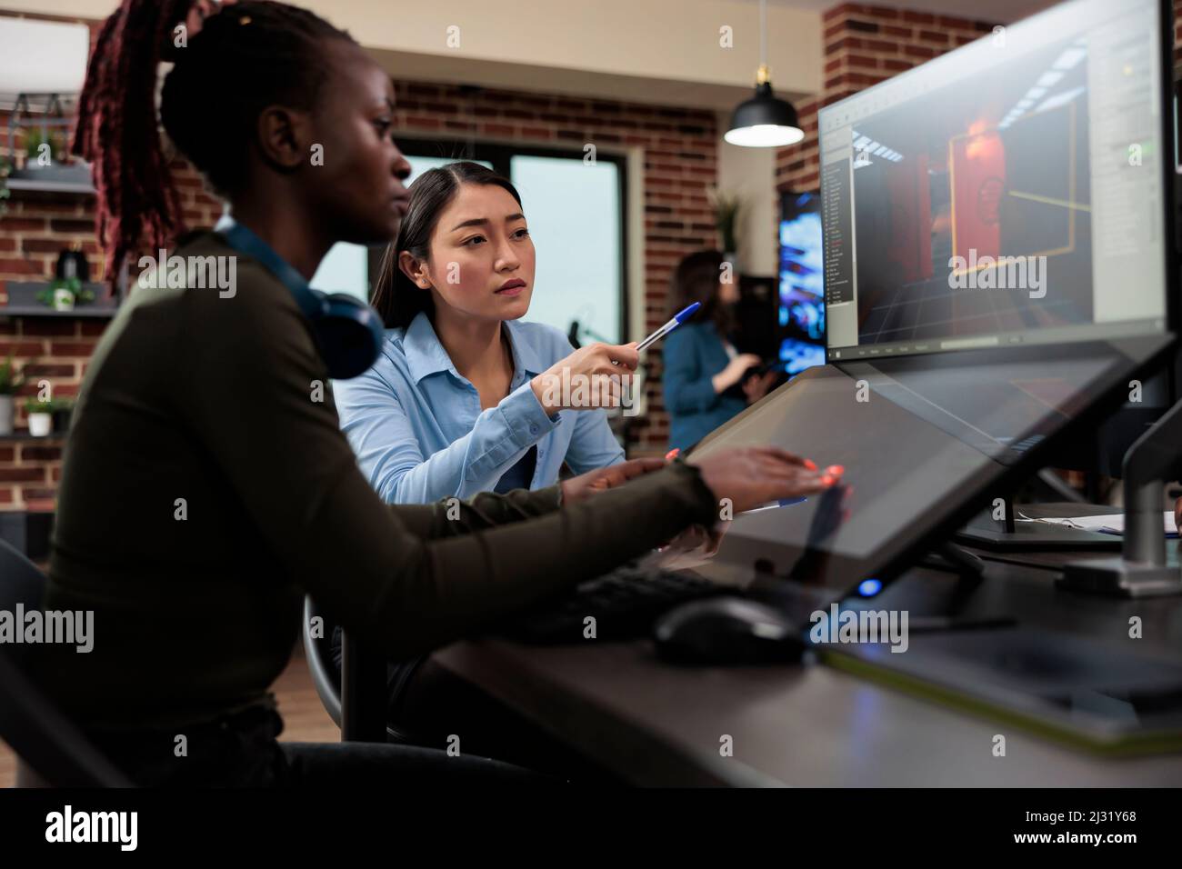 Chef d'équipe artistique du département de production 3D avec plusieurs écrans sur le bureau travaillant sur un projet de divertissement numérique. Développement de jeux créatif entreprise employé travaillant sur la conception de niveau de jeu vidéo. Banque D'Images