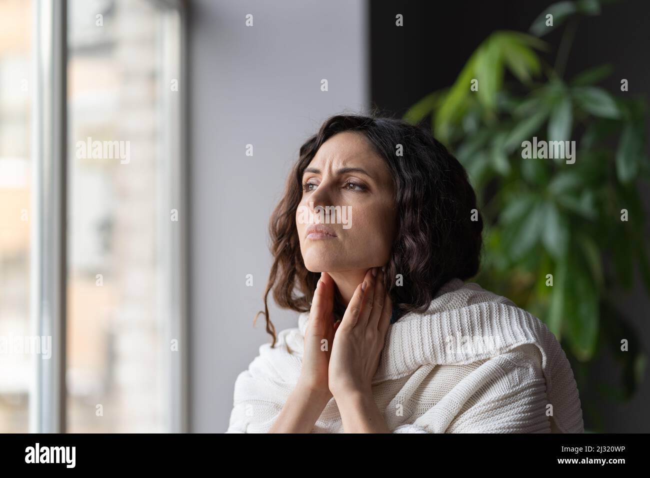 Jeune malade malsain regardant la femme souffrant de mal de gorge et de glandes enflées, regardant par la fenêtre Banque D'Images