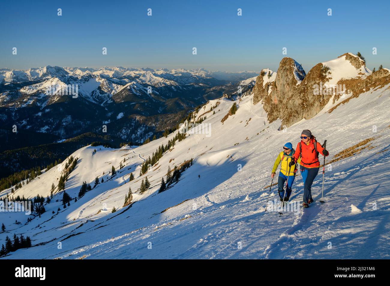 Homme et femme en randonnée jusqu'à la Rotwand via la pente de neige, tours de roche en arrière-plan, Rotwand, Spitzing zone, Alpes bavaroises, haute-Bavière, Bavière, Allemagne Banque D'Images