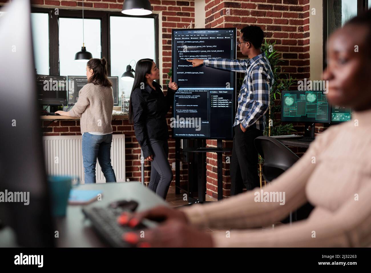 Développeur de réseau back-end afro-américain expliquant aux collaborateurs les lignes de code de l'application. Équipe développant des couches de sécurité supplémentaires afin de maintenir une bonne fonctionnalité du système. Banque D'Images