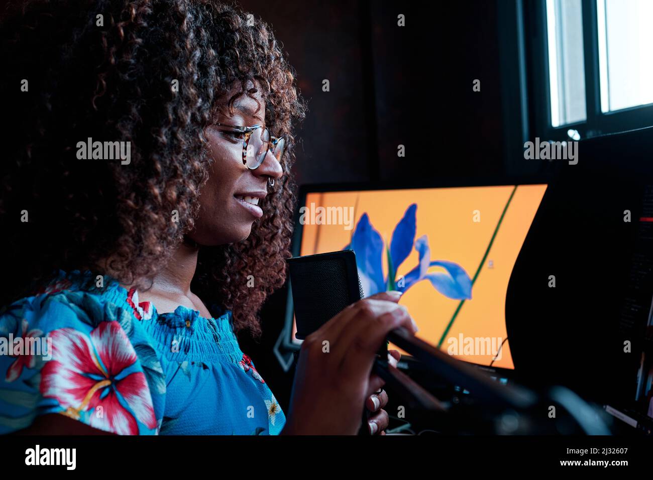 Jeune cheveux bouclés noire femme podcasting avec microphone à l'ordinateur Banque D'Images