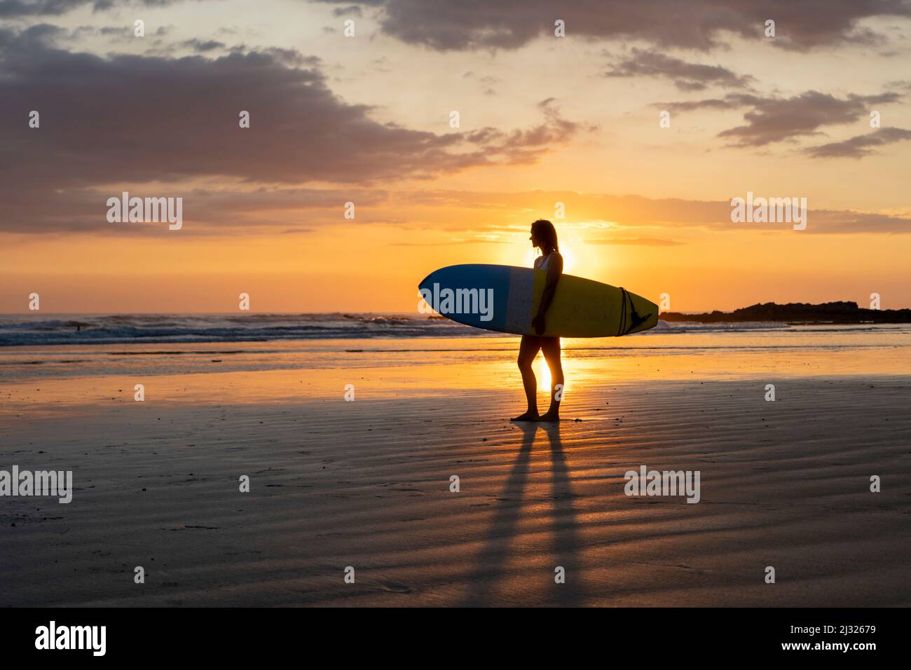 Silhouette de fille surfeuse. Surf femme marchant avec surf sur la plage. Golden hour belles couleurs Banque D'Images