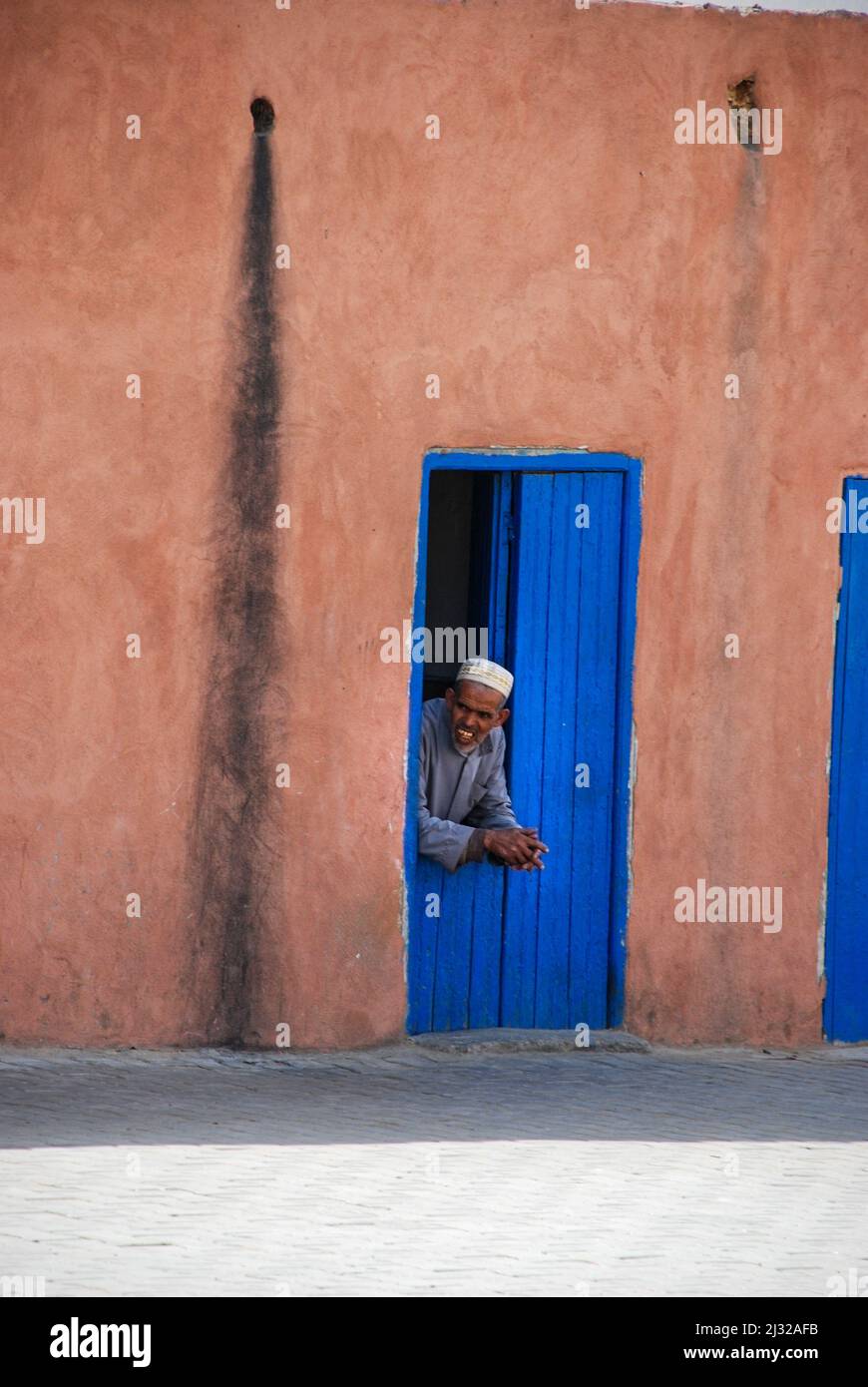 Un homme se repose à son entrée dans les rues de la Médina de Marrakech Banque D'Images