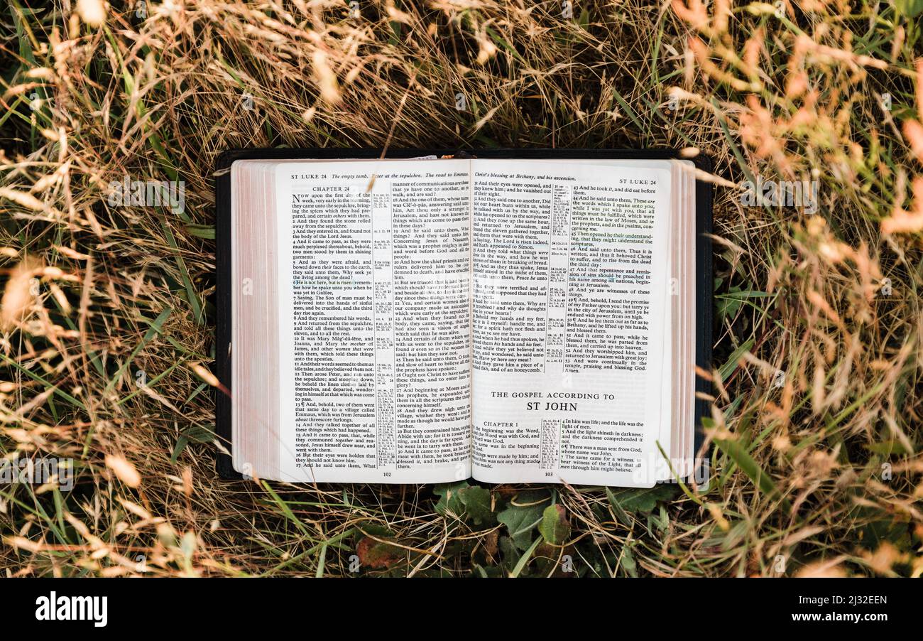 La Sainte Bible chrétienne s'ouvre dans un champ chaud et ensoleillé au livre évangélique de Saint Jean Banque D'Images
