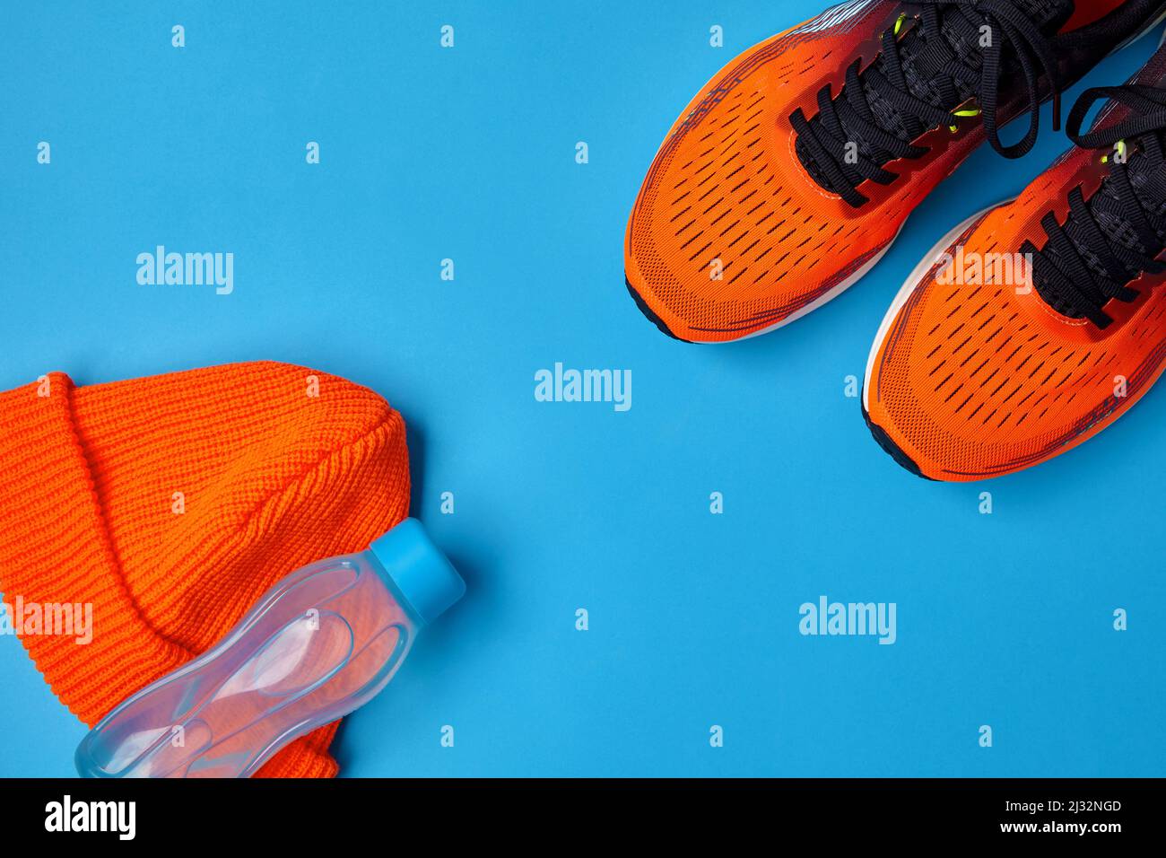 Baskets de sport orange bonnet tricoté et bouteille d'eau en plastique Banque D'Images