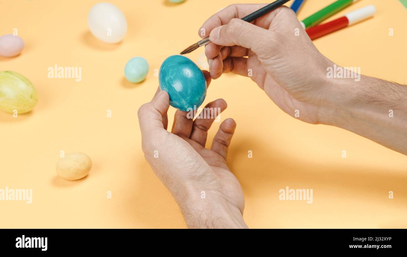 peinture à la main des œufs de pâques colorés sur fond jaune Banque D'Images