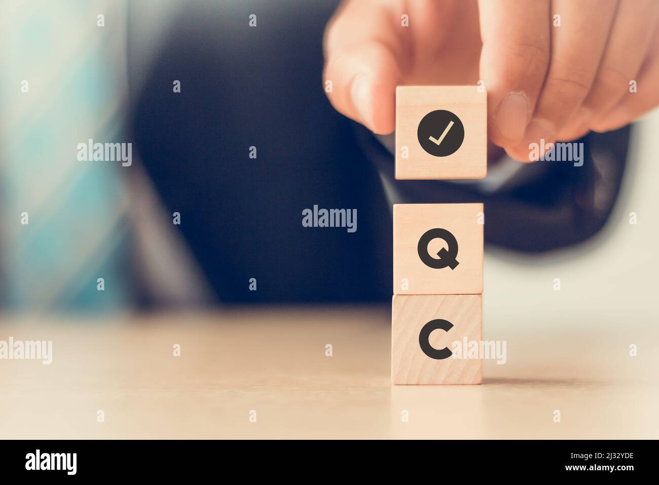 Concept de contrôle qualité (CQ). Pour les entreprises et l'industrie. Qualité standard, garantie, processus, contrôle et approbation. La main tient des cubes en bois avec un chèque Banque D'Images