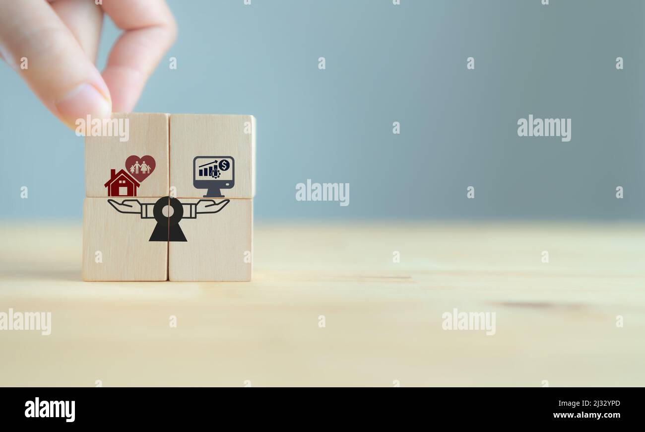 Concept d'équilibre entre vie professionnelle et vie privée. Balances pour le travail et la maison. Travail de comparaison, finance et famille. Main met les cubes en bois avec l'icône de travail-vie balancey sur gris Banque D'Images
