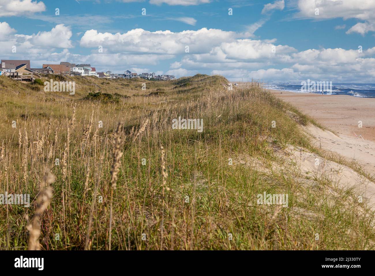 Outer Banks, Caroline du Nord. Sandy Ridge stabilisée par des oats de mer et d'autres végétaux sépare les maisons de vacances de l'océan Atlantique. Banque D'Images