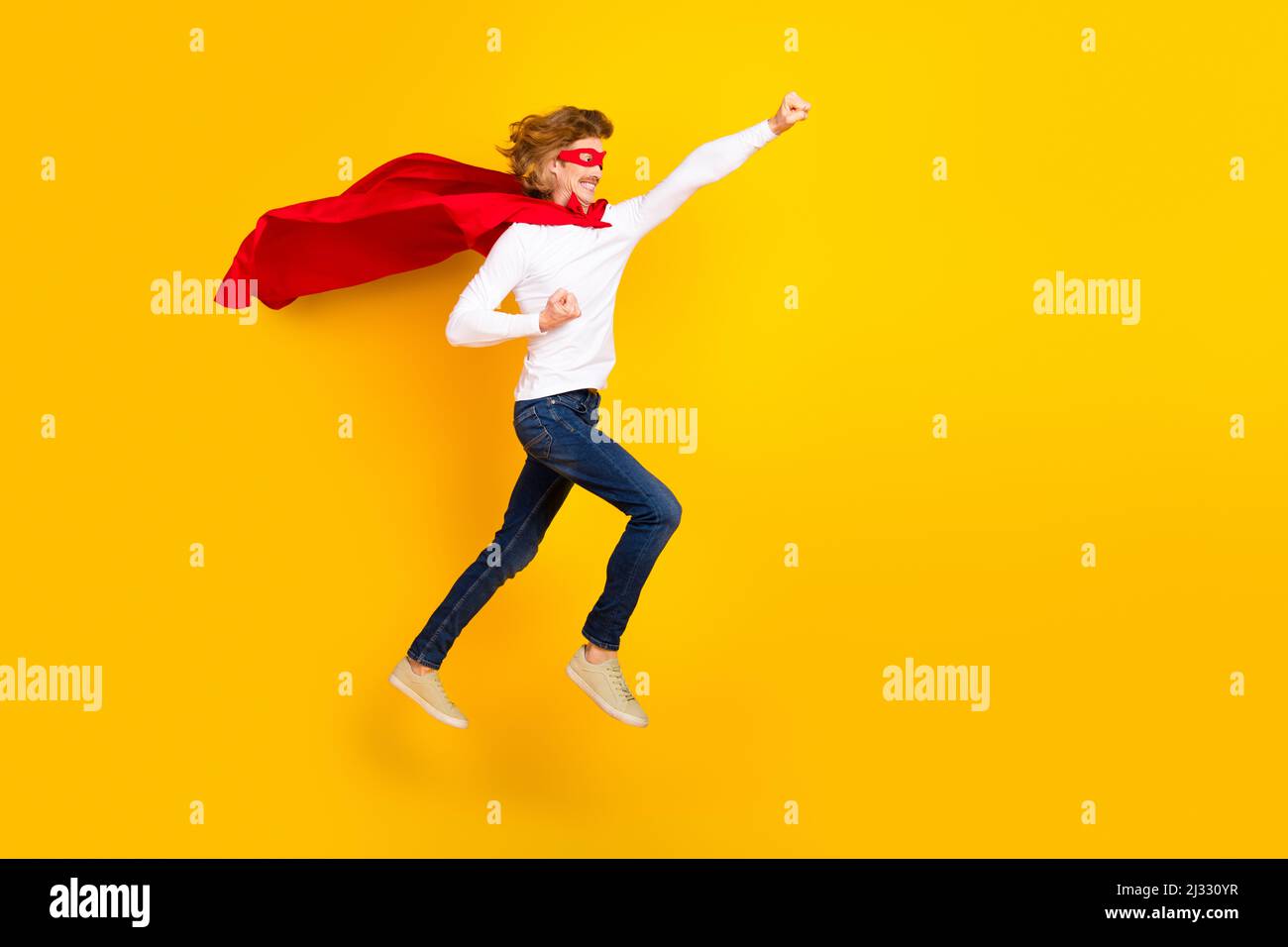 Photo de côté pleine taille d'un homme insouciant en costume de super-homme comportement puéril isolé sur fond jaune Banque D'Images