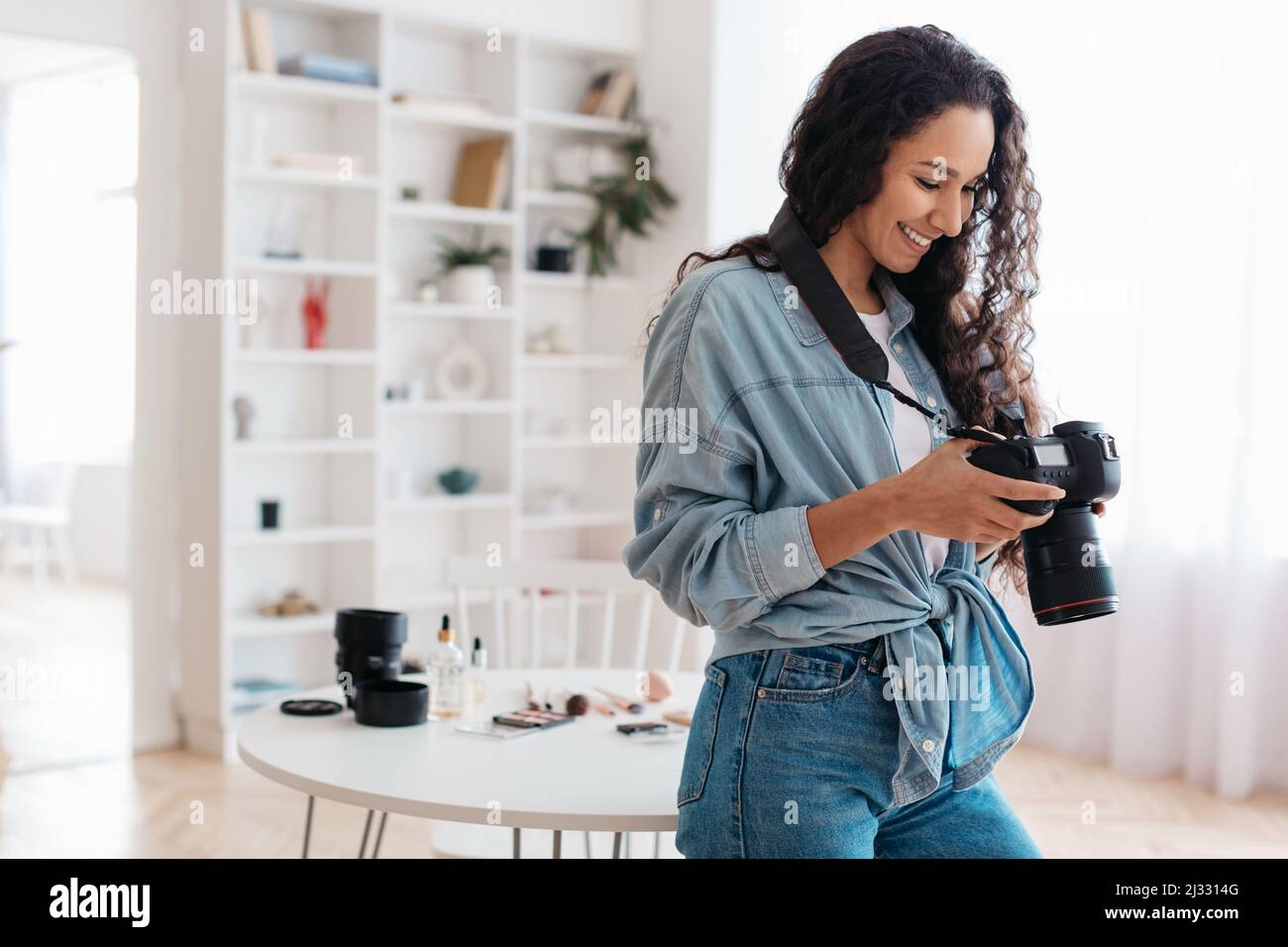 Photographe femme tenant l'appareil photo travailler prendre des photos debout à la maison Banque D'Images