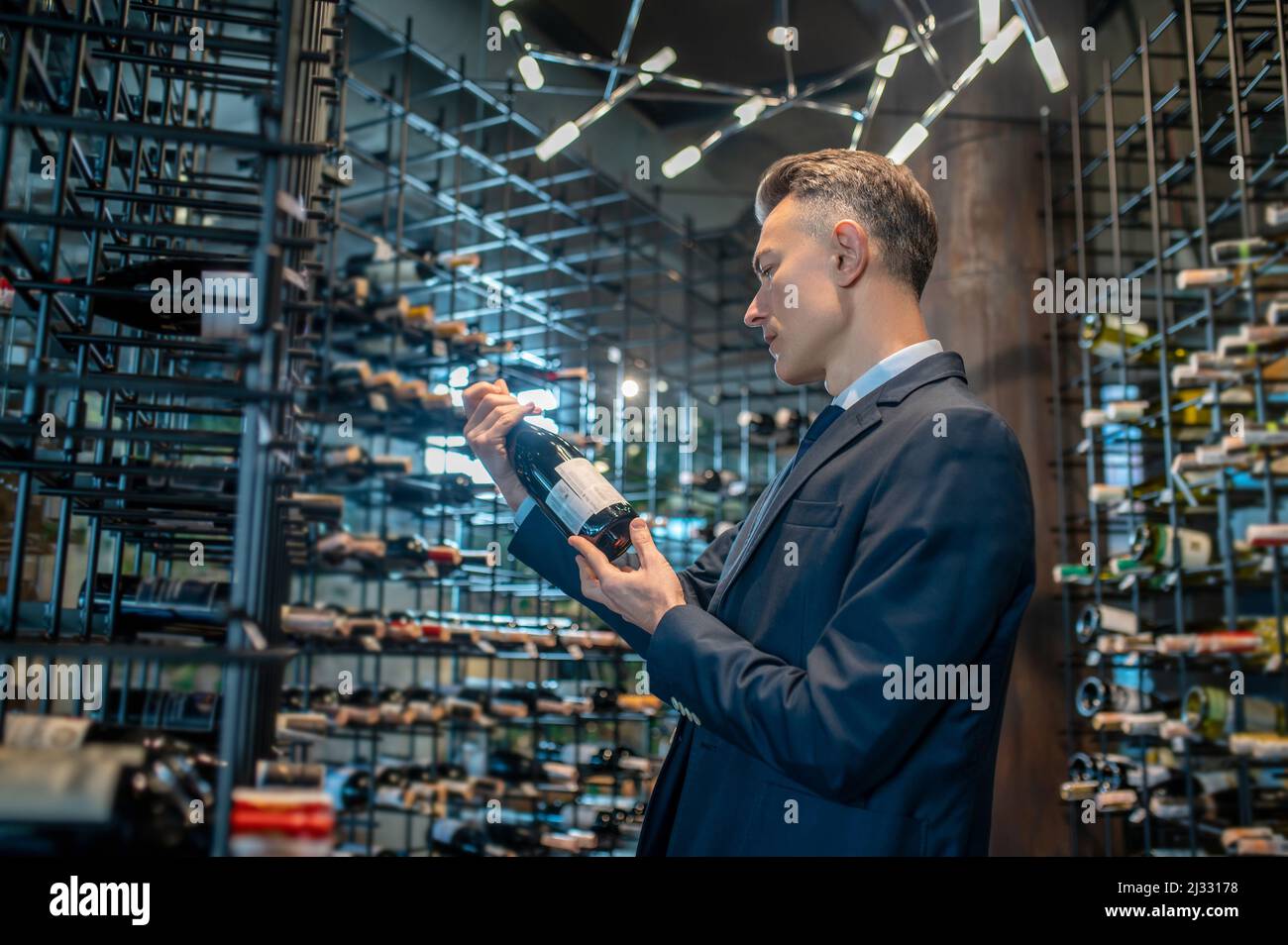 Un homme qui choisit une bouteille de vin dans un magasin de vin Banque D'Images