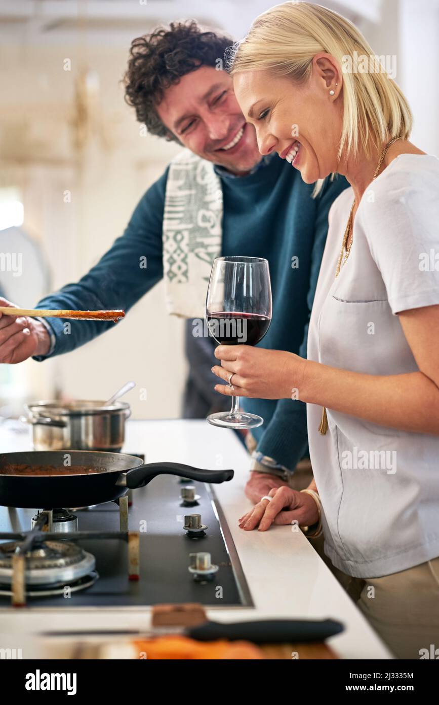 Tout a un meilleur goût quand vous êtes amoureux. Photo d'un couple heureux qui cuisine le dîner ensemble dans leur cuisine. Banque D'Images