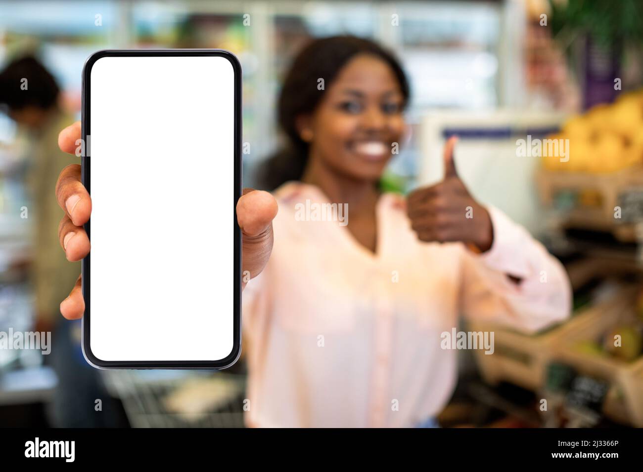 African Female montrant l'écran de téléphone portable Publicité Shopping application dans le supermarché Banque D'Images