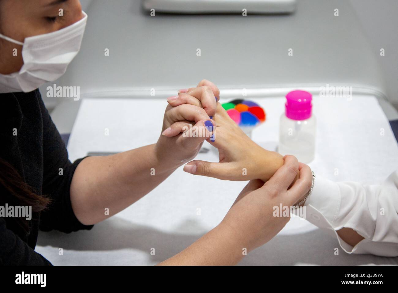 Femme avec masque donnant un massage manuel. Jeune fille recevant un massage. Clinique esthétique. Manucure Banque D'Images