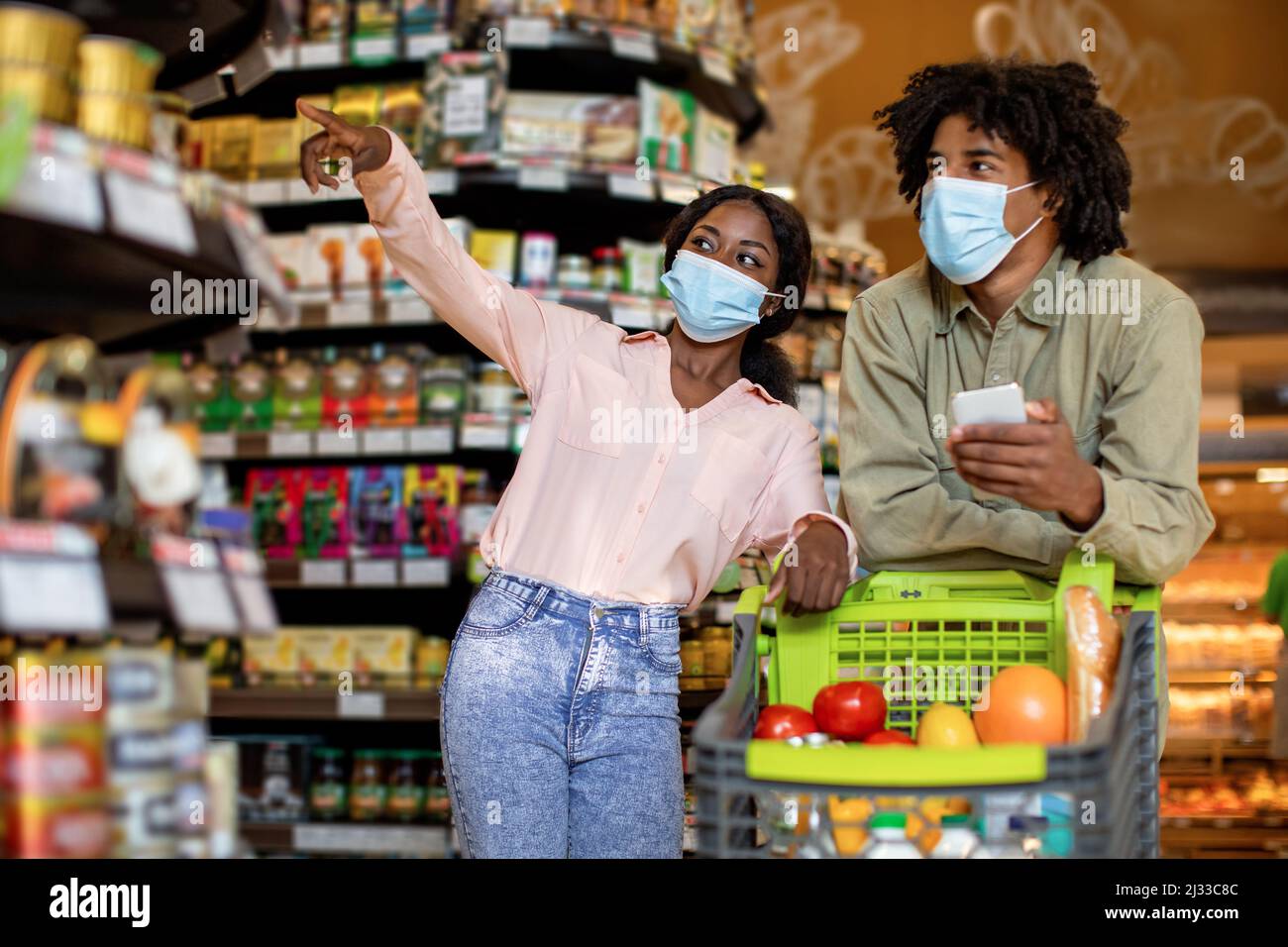 Femme noire montrant quelque chose au mari faire des courses au supermarché Banque D'Images
