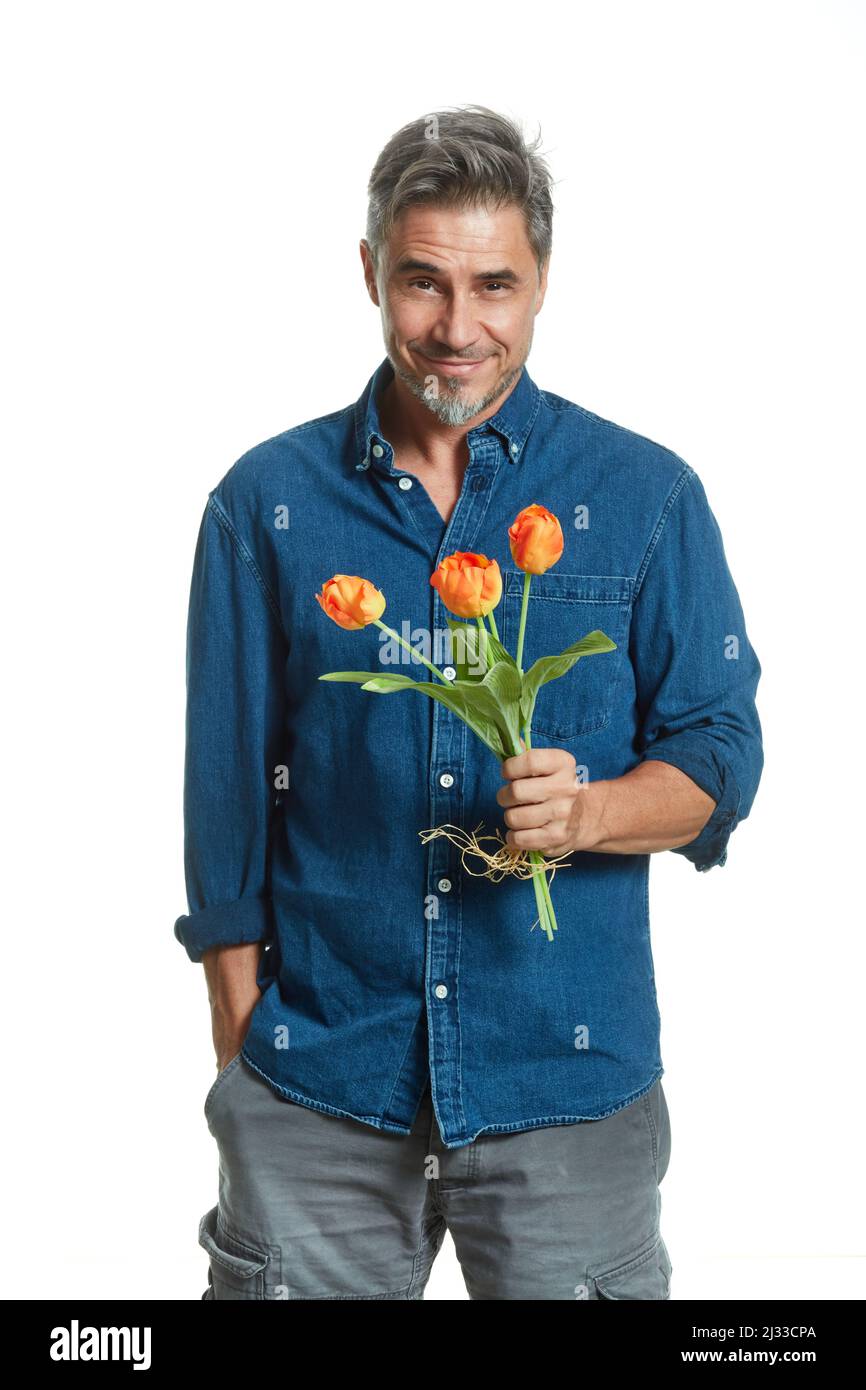 Homme blanc plus ancien décontracté tenant bouquet de fleurs, tulipes, isolé sur blanc, souriant. Banque D'Images