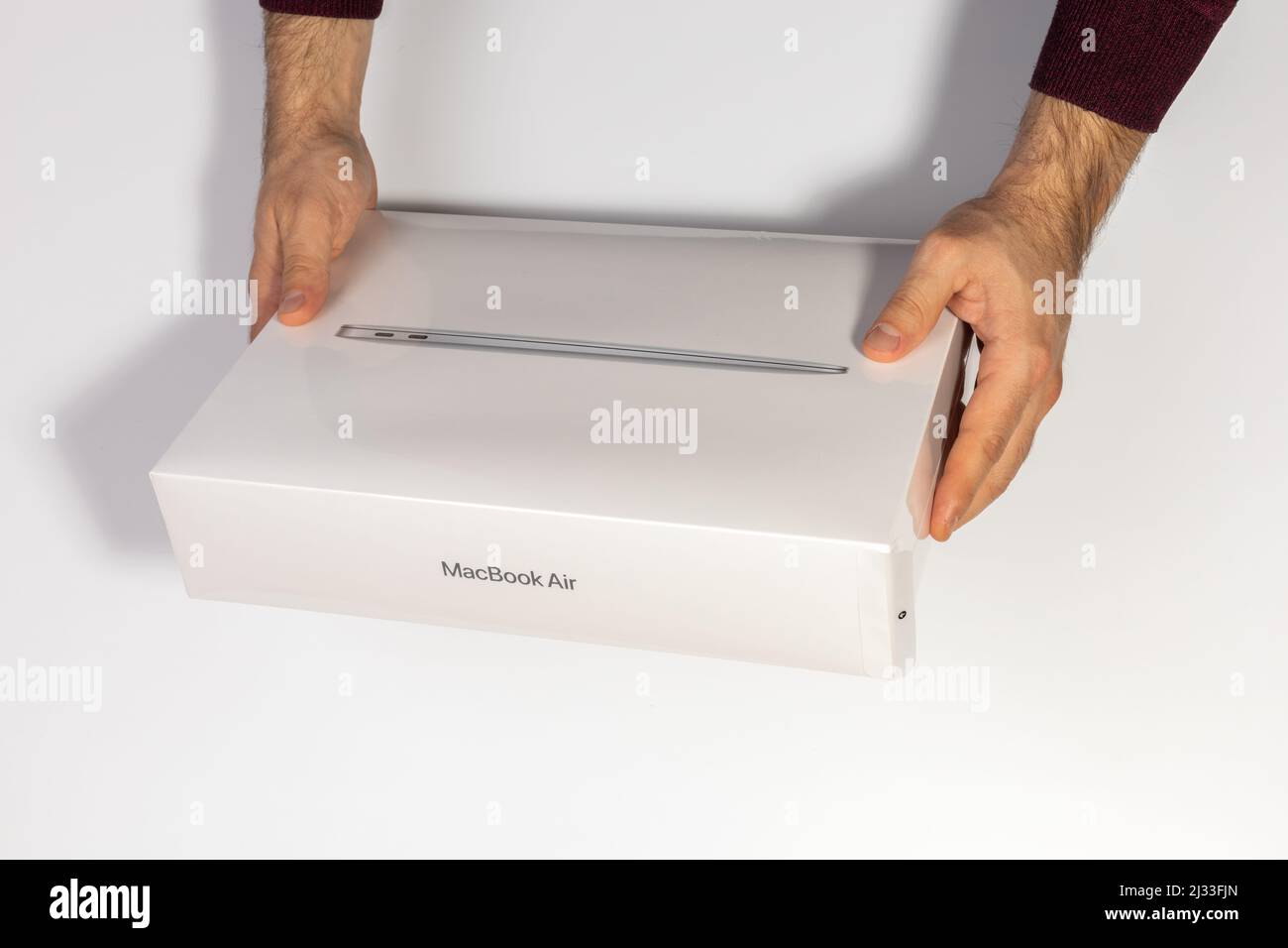 Saratov, Russie - 26 février 2022 : tenir l'emballage de protection avec le nouveau MacBook Air 13 pouces moderne avec processeur M1 topview, fond blanc Banque D'Images