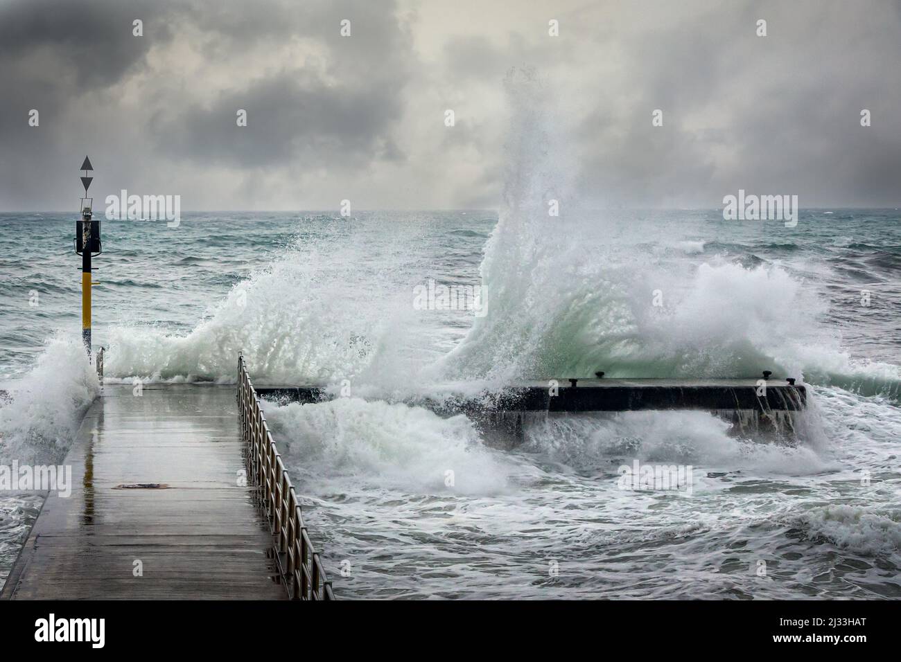 Vagues de tempête sur l'océan éclaboussant sur un quai pendant une tempête hivernale Banque D'Images