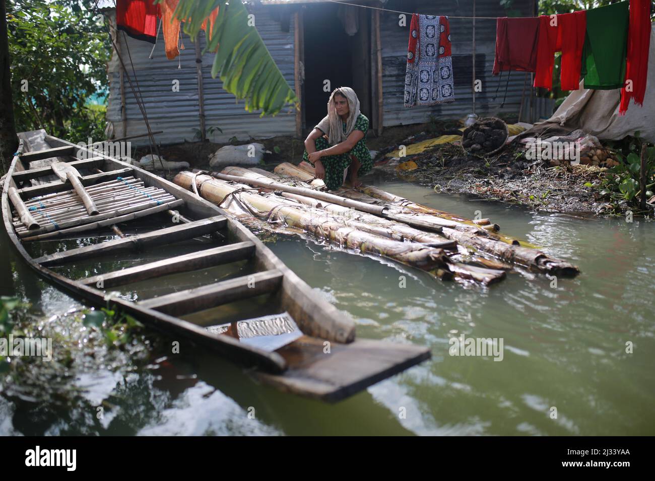 Une femme est assise sur un radeau de fortune devant sa maison inondée à Sunamganj, dans le nord-est du Bangladesh, le 16 juillet 2020. Chaque année, des millions de personnes touchées par les inondations dues à de fortes pluies et à des cours d'eau débordant dans les parties nord-est et nord-ouest du Bangladesh. De nombreuses personnes sont mortes, déplacées, ont perdu leurs récoltes, leurs maisons, souffrent de nourriture et d'eau potable pure pendant l'inondation de la mousson. Banque D'Images