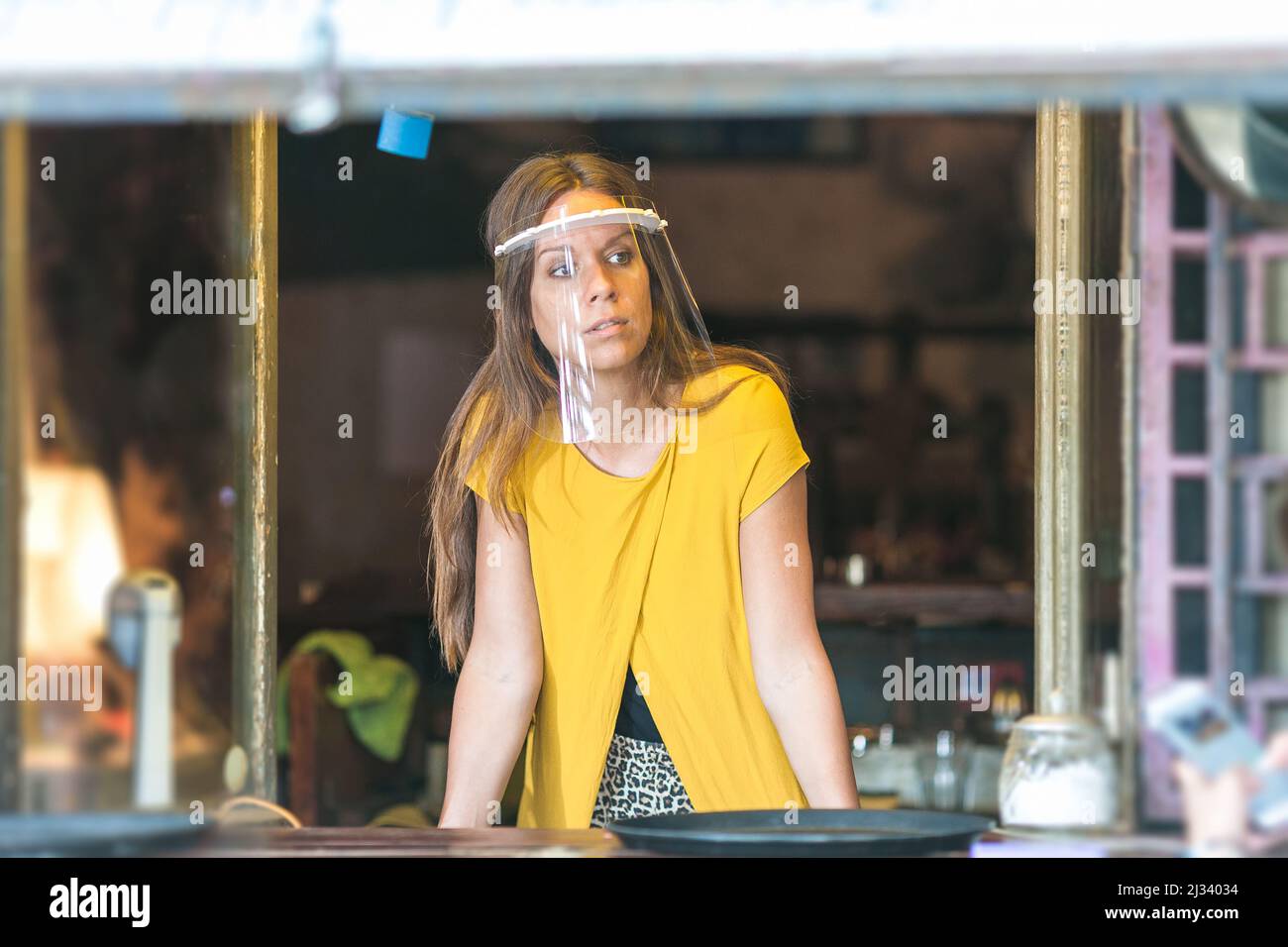 jeune femme dans un café vide portant une visière de protection Banque D'Images
